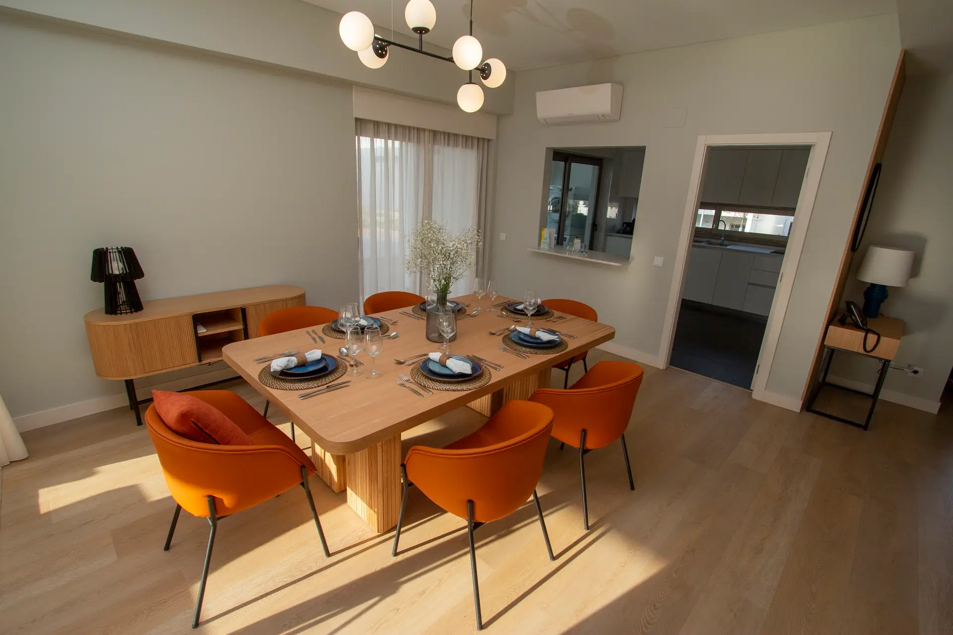 Modern dining room with orange chairs and wooden table.